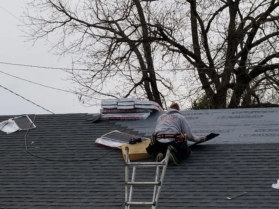 Worker installing new shingles for roof replacement